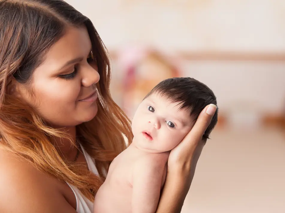 Mum holding newborn during daily routine, supporting newborn care and daily rhythm advice