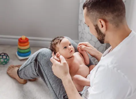 Dad playing with newborn on lap, promoting early play and sensory development in newborns