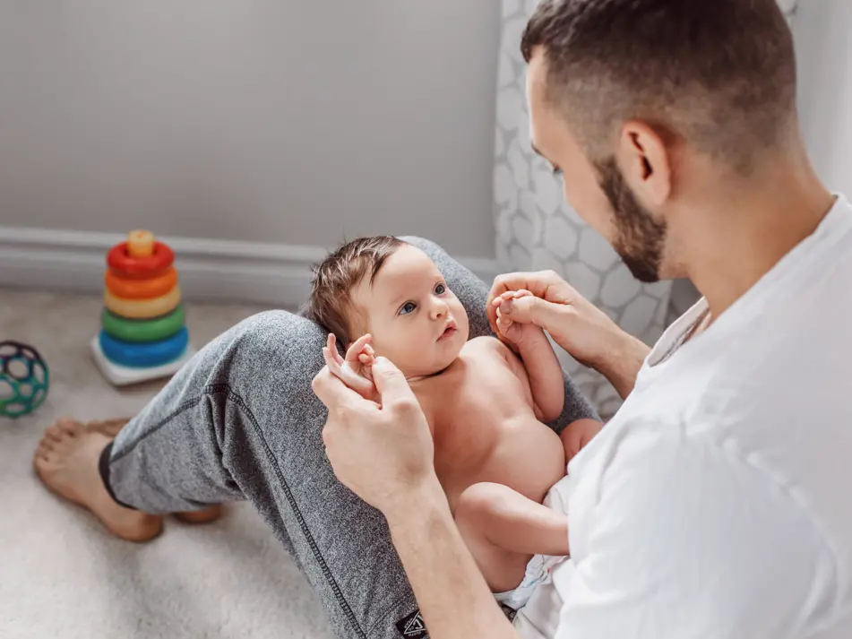 Dad playing with newborn on lap, promoting early play and sensory development in newborns
