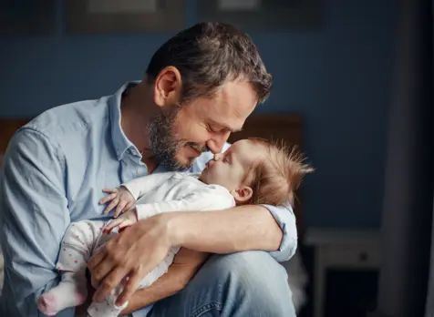 Baby sleeping in dad's arms, supporting baby sleep tips and settling routines for parents